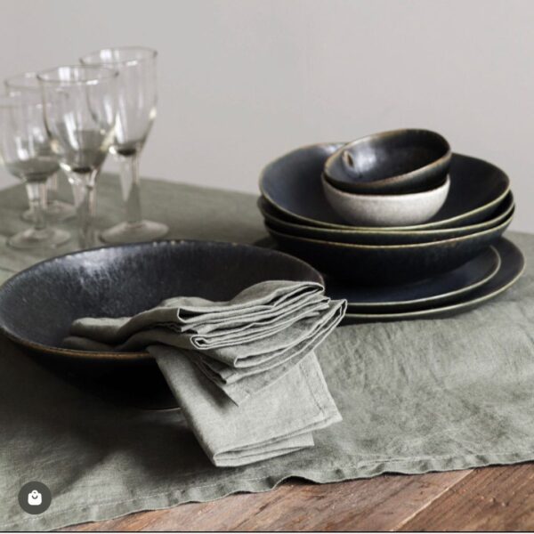 tavolo apparecchiato con tovaglioli e tovagliette americane in lino e servizio di piatti in gres color nero