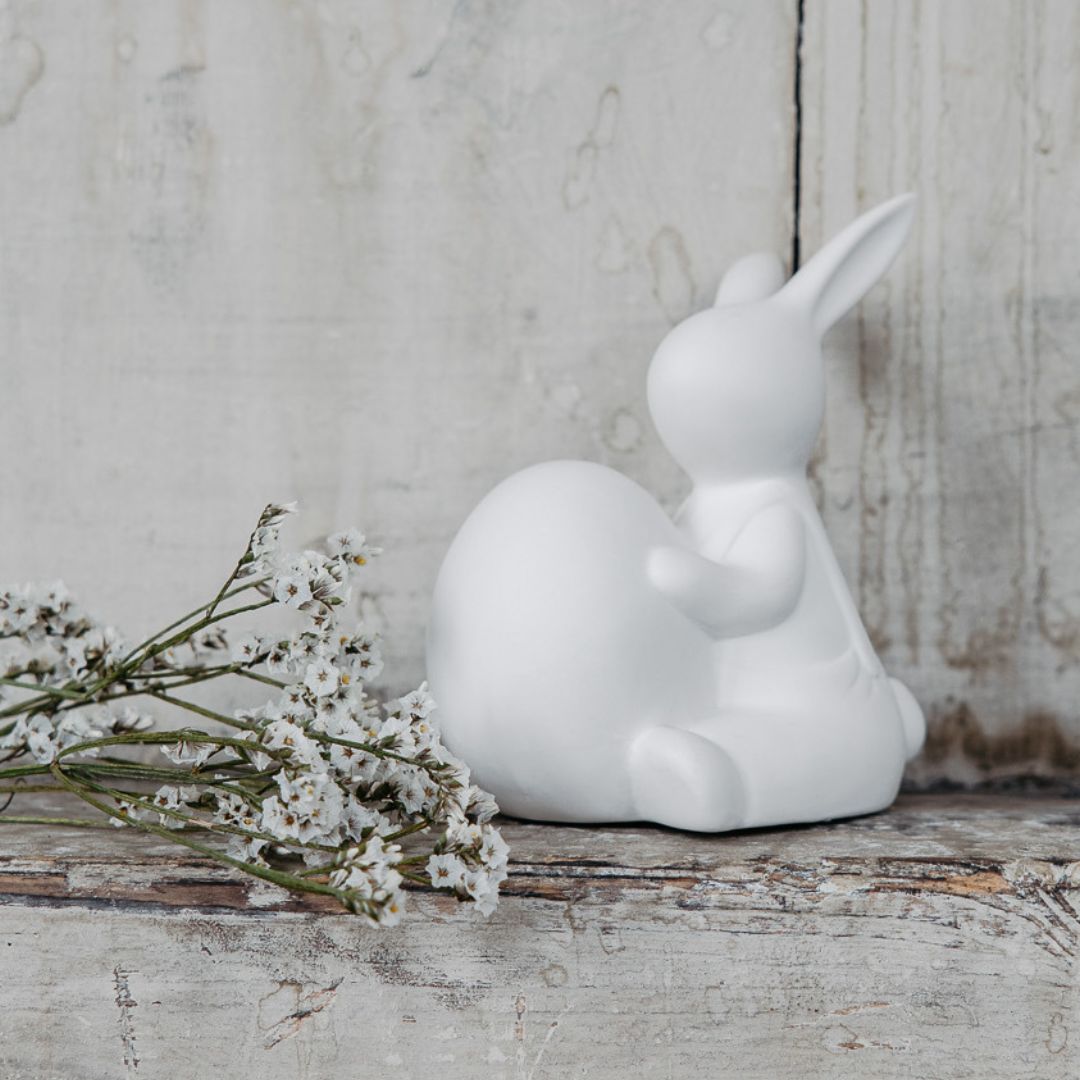 simpatica decorazione pasquale raffigurante un coniglietto che abbraccia un uovo. Tutto in ceramica bianca opaca
