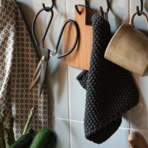angolo cucina attrezzato con strocfinacci, tazze e presina in cotone lavorata a maglia in stile danese punto riso