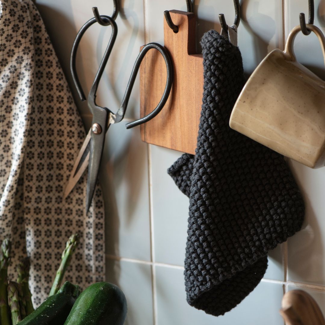 angolo cucina attrezzato con strocfinacci, tazze e presina in cotone lavorata a maglia in stile danese punto riso