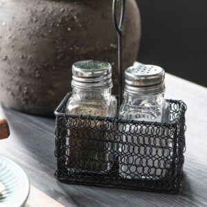 cestino in legno intrecciato di colore nero contenente un set per sale e pepe in vetro trasparente con tappo dosatore in acciaio inossidabile
