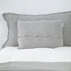 copricuscino di design nordico lavorato a maglia color grigio chiaro chiuso sul davanti da quattro bottoni in legno naturale