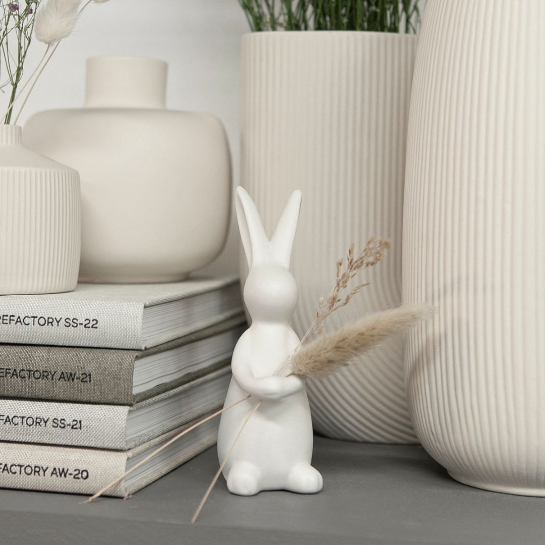 decorazione pasquale a forma di coniglietto in piedi in ceramica bianca opaca che abbraccia un rametto di verde