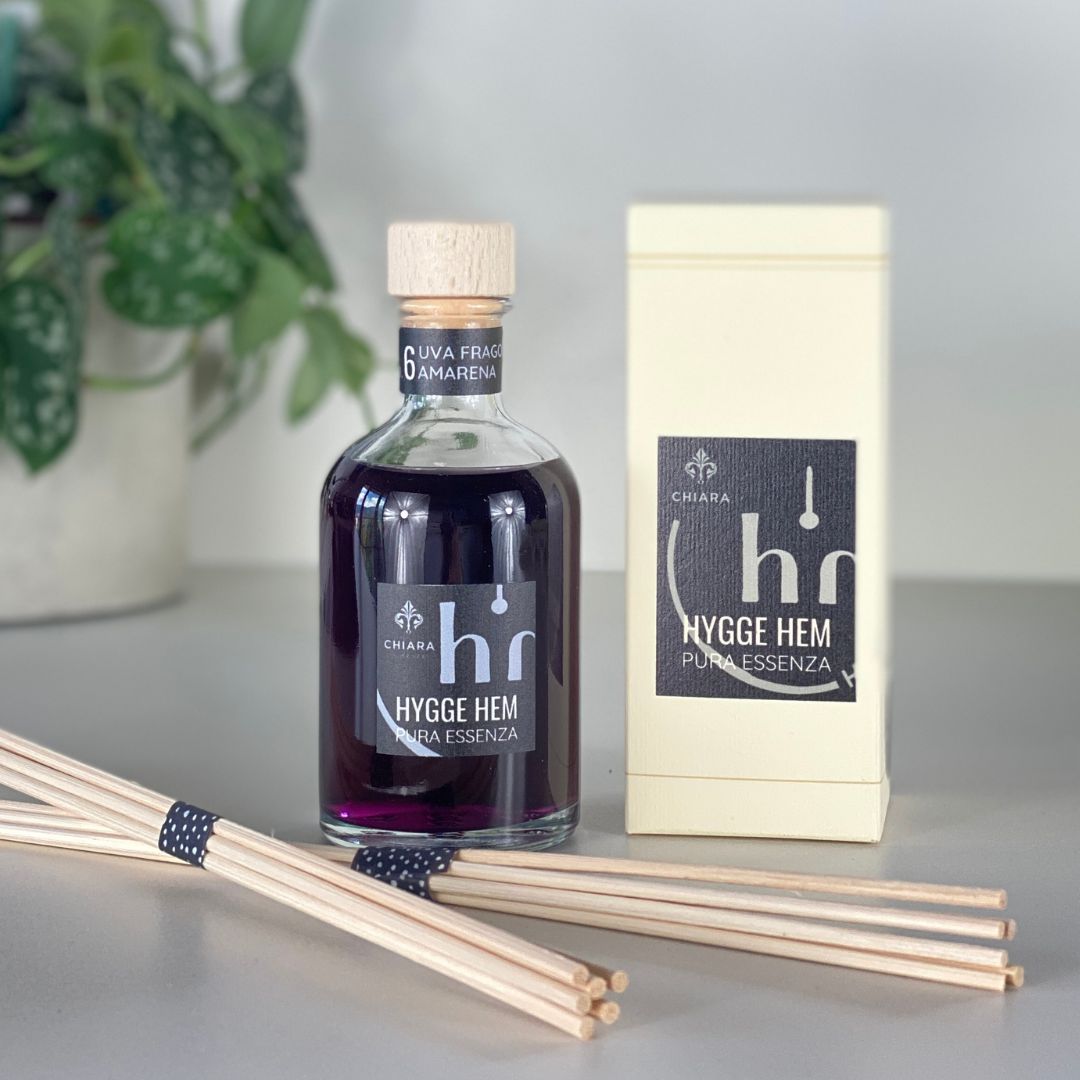 fragranza d'ambiente con diffusore a bastoncini in legno in bottiglia di vetro trasparente e tappo in legno da 100 ml all'uva fragola e amarena della linea PURA ESSENZA di HYGGE HEM