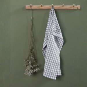 Strofinaccio da cucina in cotone riciclato appeso ad un porta strofinacci con motivo a quadri bianchi e grigio chiaro