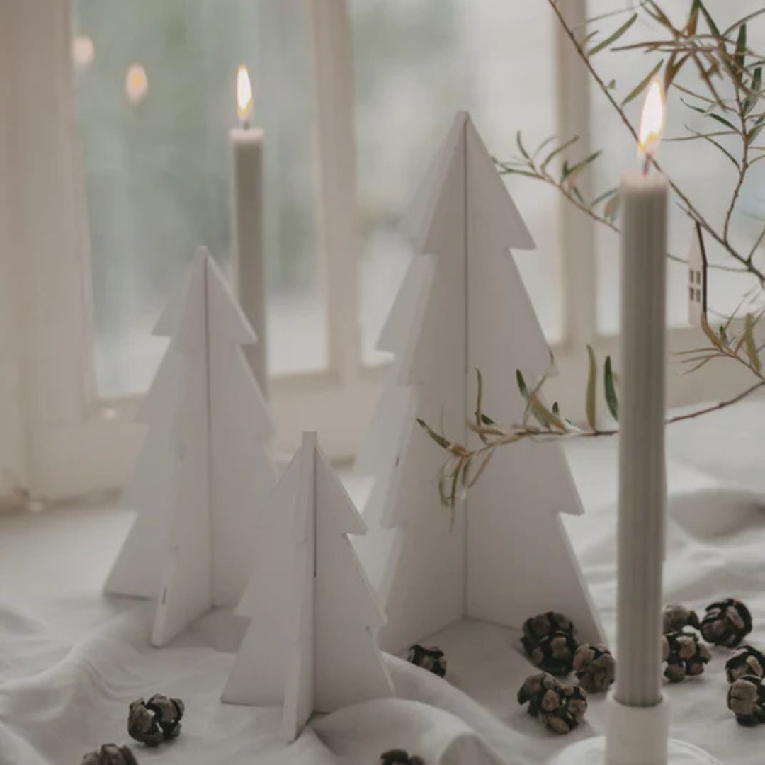 paesaggio natalizio con tre alberi di natale in legno smaltato bianco e candele accese