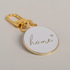 portachiavi di design con montatura color oro e medaglione smaltato bianco con incisa la parola "home"