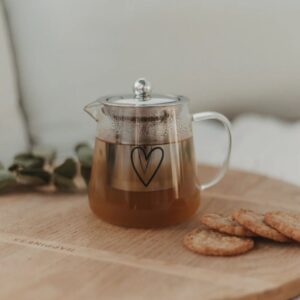 teiera di design in vetro borosilicato trasparente e filtro con coperchio in acciaio inossidabile, sul fronte della teiera c'è un'elegante stampa in nero di un cuore stilizzato
